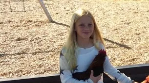 A young student with a hen on a school playground