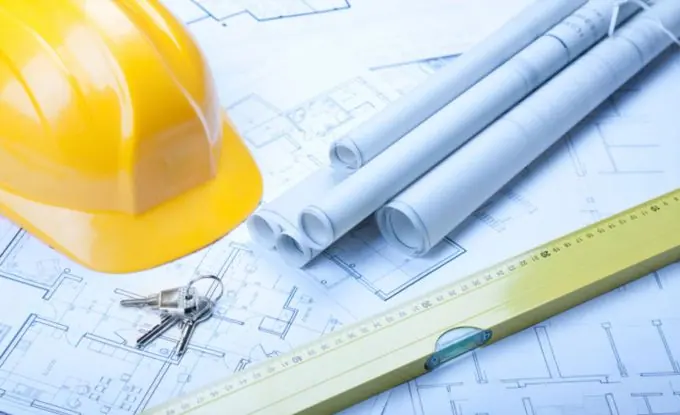 Hard hat, rolled blueprints and keys on a set of building plans