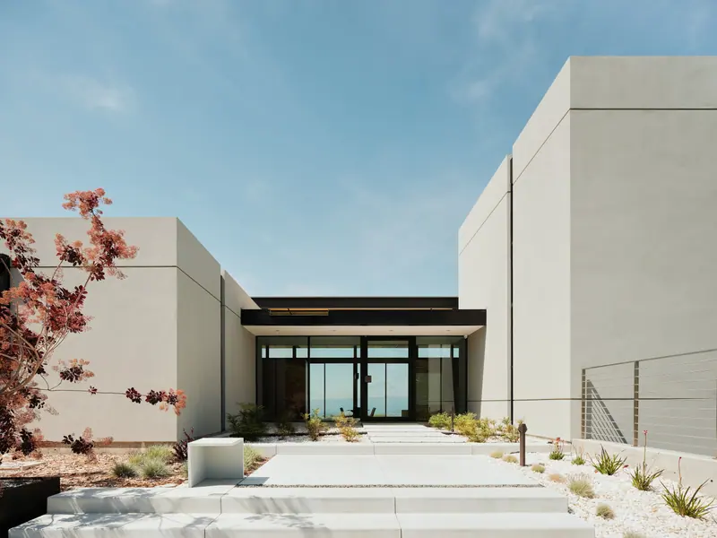 Board-formed concrete walls frame a quiet courtyard entry beside a Japanese maple