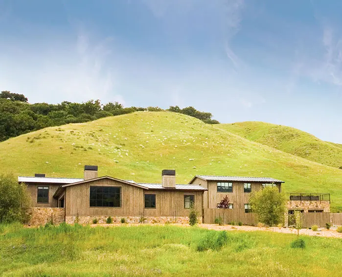 Board-and-batten ranch house below rolling green hills