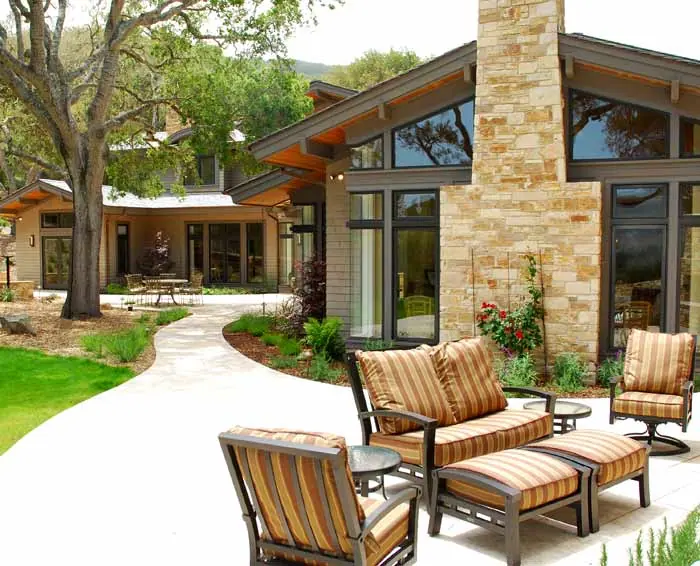 Stone chimney, cantilevered roofs and a courtyard with striped lounge chairs