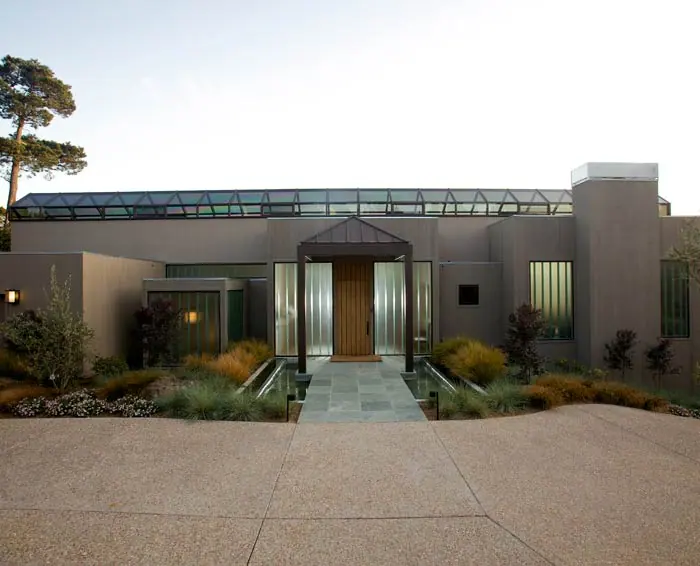 Garden court leading to a warm timber entry door beneath a long, low roof