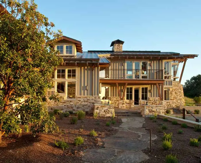 Stone-based home with timber and steel balconies set into a landscaped hillside