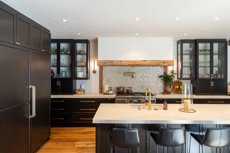 Kitchen with dark cabinetry, a reclaimed timber beam and a pale stone island