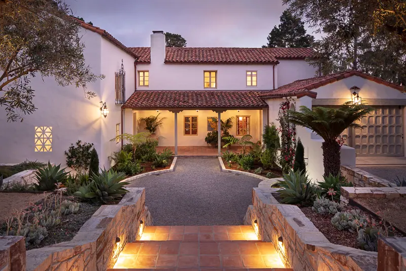 Spanish-style villa entry lit by stone steps and lanterns at twilight