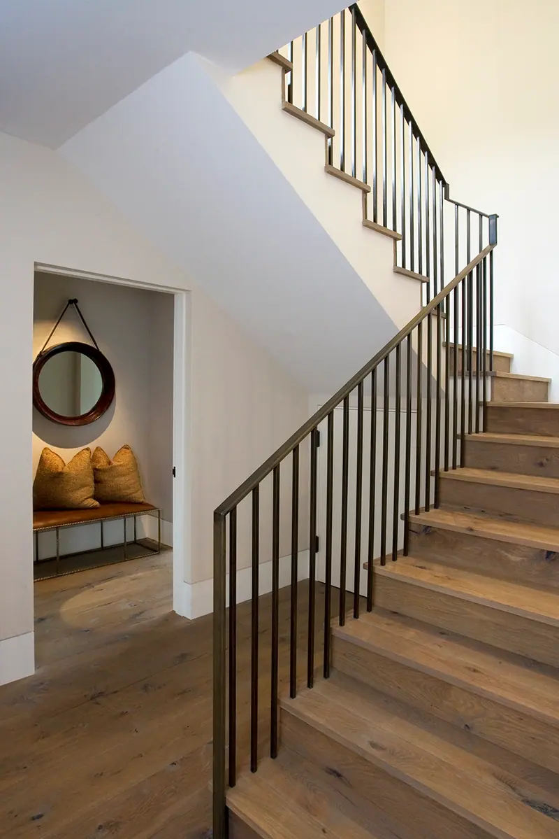Oak stair with a blackened steel balustrade rising from a cozy entry