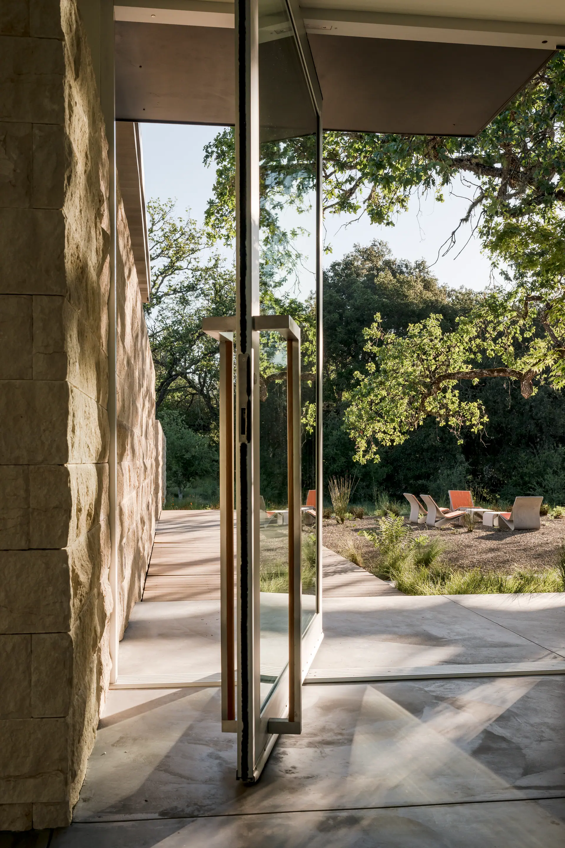 Tall metal door pull on a limestone wall opening to a garden