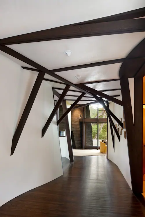 Dark timber brackets angle across a curving white hallway