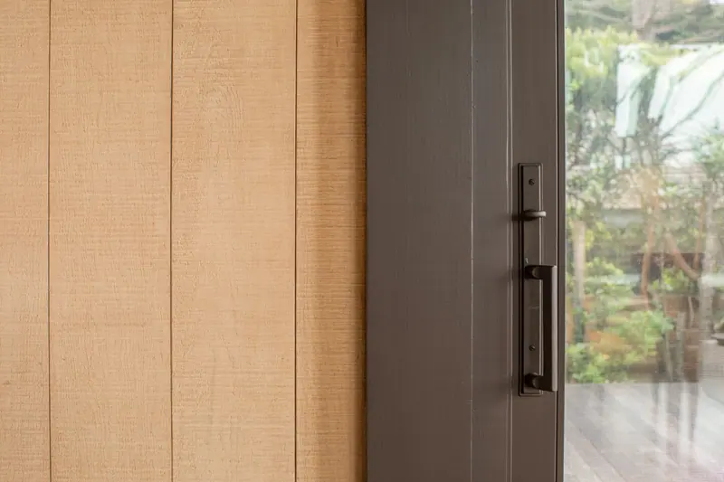 Rough-sawn timber panels beside a steel door handle