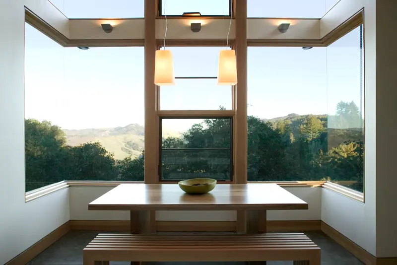 Breakfast nook with a built-in table and pendant lights facing wooded hills