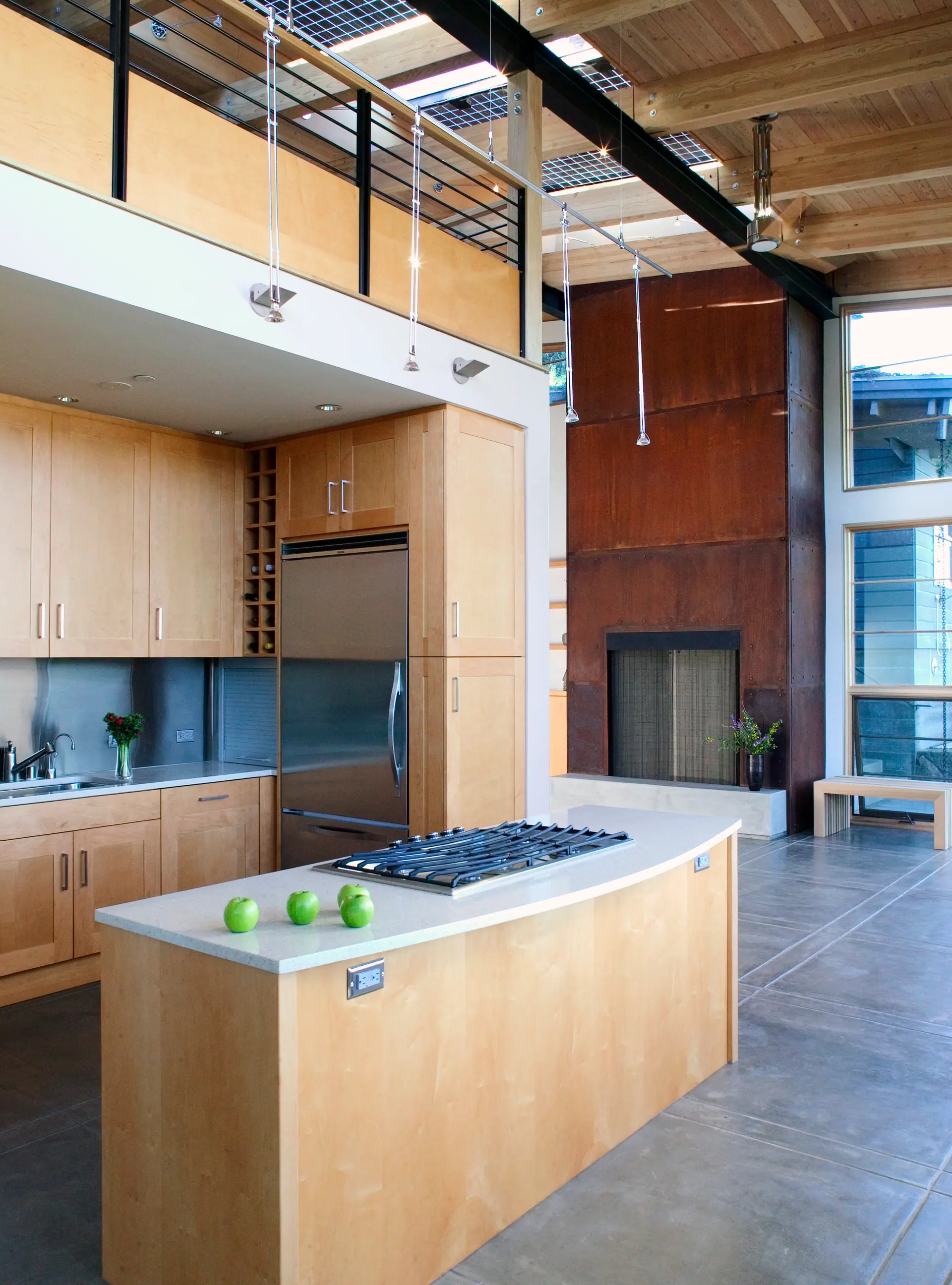 Kitchen with a curved island, maple cabinetry and a rust-colored steel wall