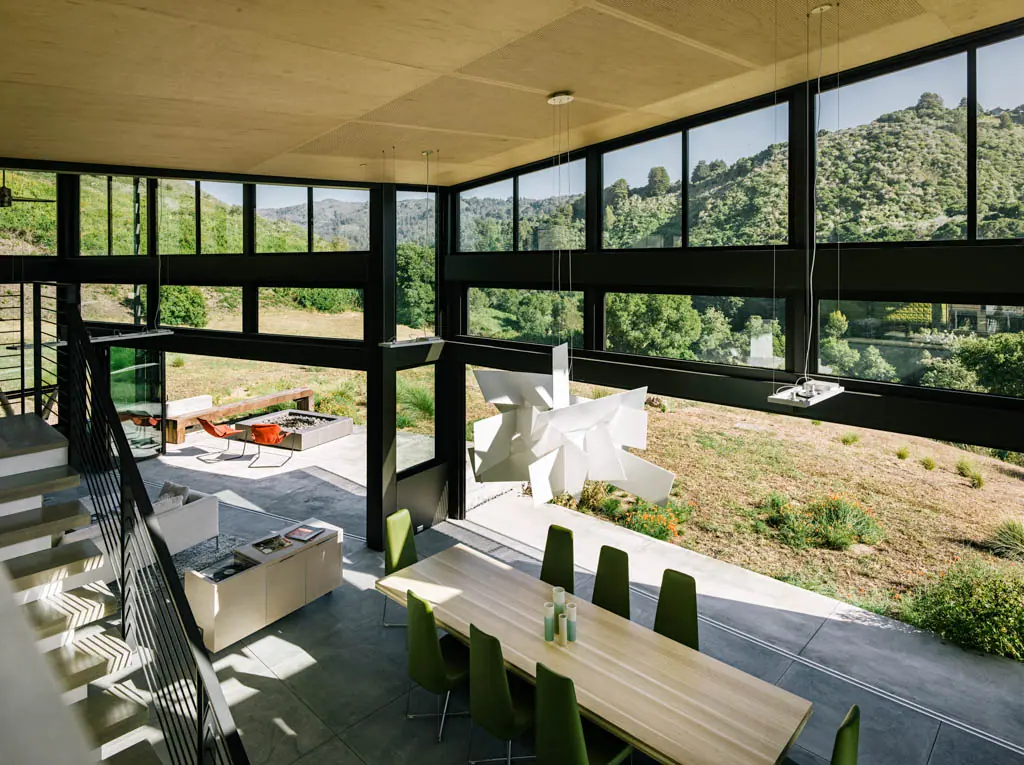 Open living space with glass walls overlooking green hills